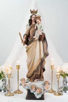 May include: A religious statue of a woman holding a child, both wearing gold crowns. The woman is dressed in a brown and beige robe, holding a gold scepter. The statue rests on a base with cherubs. Lit candles and flowers surround the statue.