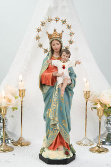 May include: A religious statue of the Virgin Mary holding baby Jesus. The statue features a gold crown and halo, and is dressed in a blue and orange robe with gold accents. The baby Jesus is wearing a white outfit with a red heart.